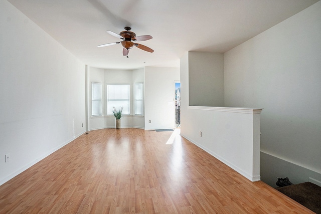 empty room featuring baseboards, a ceiling fan, and light wood finished floors