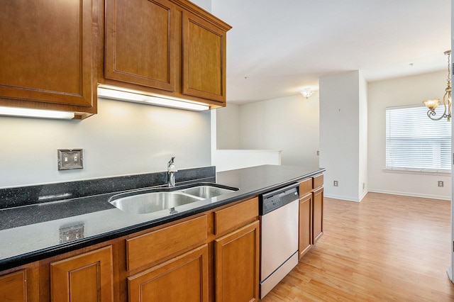 kitchen featuring brown cabinetry, light wood finished floors, a sink, dishwasher, and a notable chandelier