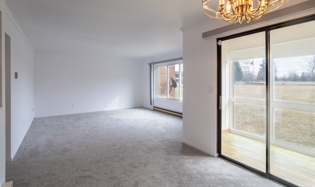 carpeted empty room with an inviting chandelier, a baseboard radiator, baseboards, and ornamental molding