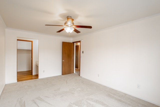 unfurnished bedroom with carpet floors, ornamental molding, a spacious closet, and a ceiling fan