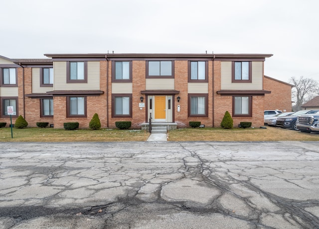 view of property featuring a front yard and brick siding