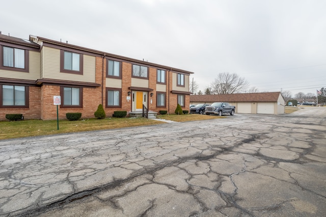 townhome / multi-family property featuring a garage, an outbuilding, and brick siding