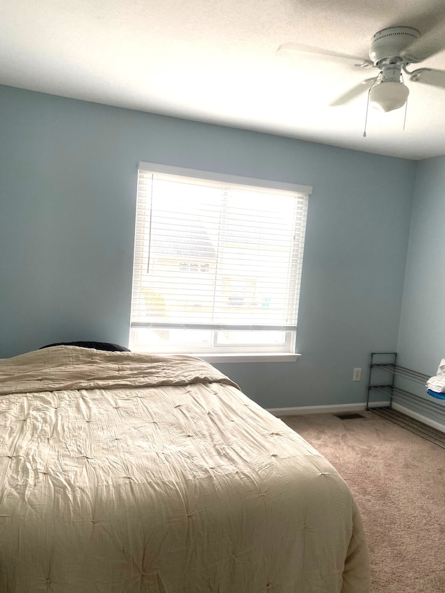 carpeted bedroom with visible vents, baseboards, and ceiling fan