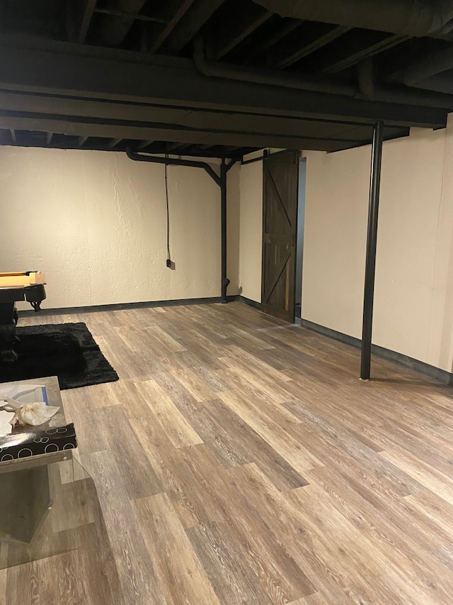 finished basement with a barn door and wood finished floors