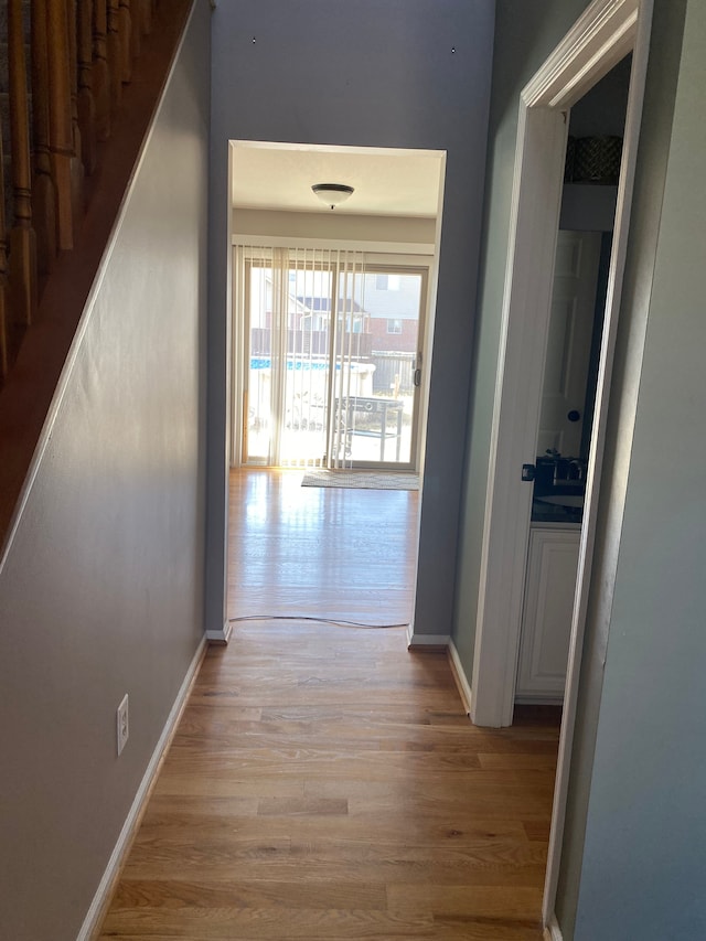 hall featuring stairway, baseboards, and light wood finished floors