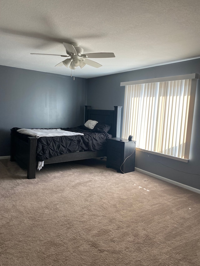 carpeted bedroom with baseboards, a textured ceiling, and a ceiling fan