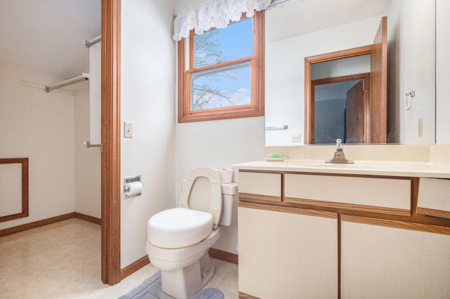 bathroom with baseboards, vanity, and toilet