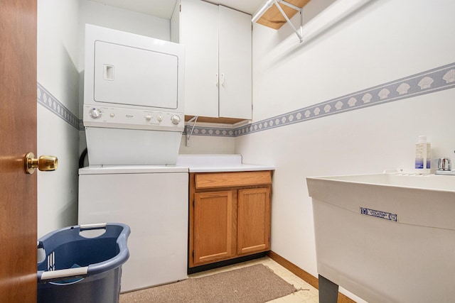 laundry room with stacked washing maching and dryer, a sink, cabinet space, and baseboards