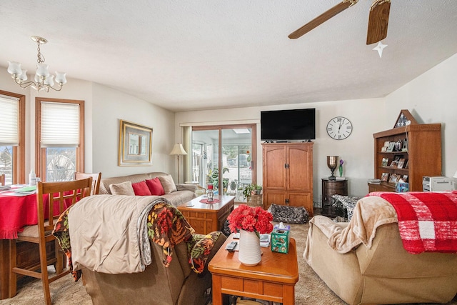 carpeted living room featuring a textured ceiling, a wealth of natural light, and ceiling fan with notable chandelier