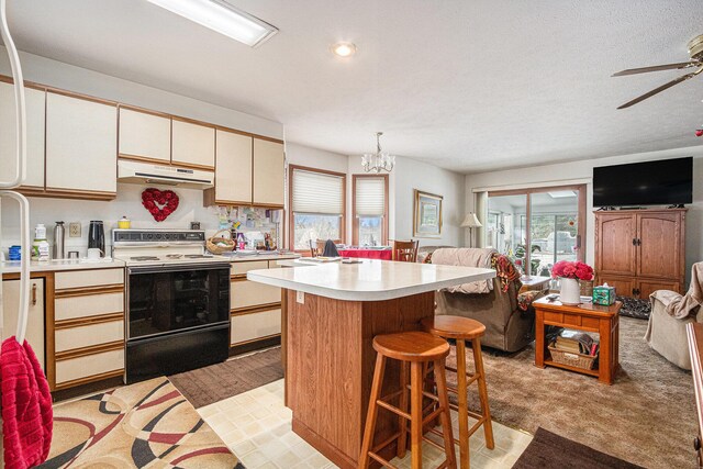 kitchen featuring white electric range oven, under cabinet range hood, open floor plan, and light countertops