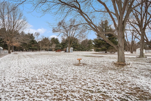 yard layered in snow featuring a storage shed and an outbuilding