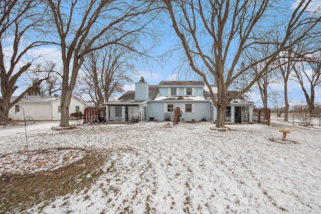 view of front of house featuring a sunroom, fence, and a chimney