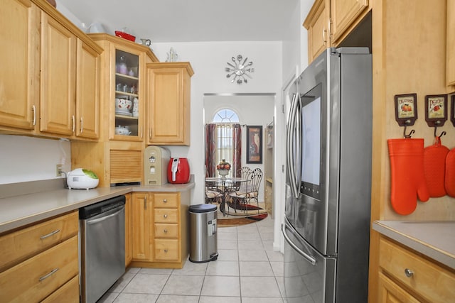 kitchen featuring light tile patterned floors, stainless steel appliances, glass insert cabinets, and light countertops