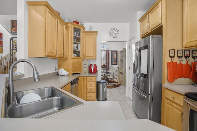 kitchen featuring light brown cabinets, a sink, appliances with stainless steel finishes, light tile patterned floors, and glass insert cabinets