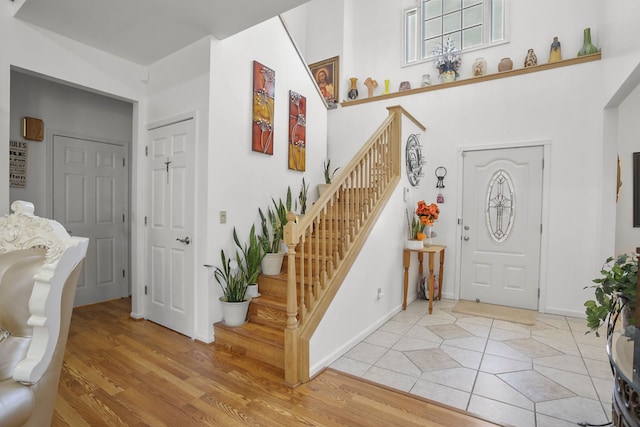 foyer with stairs, light wood-style flooring, and baseboards