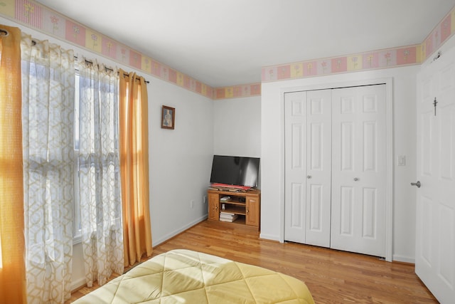 bedroom with a closet, baseboards, and wood finished floors