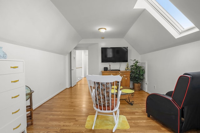 sitting room with vaulted ceiling with skylight, baseboards, and light wood finished floors