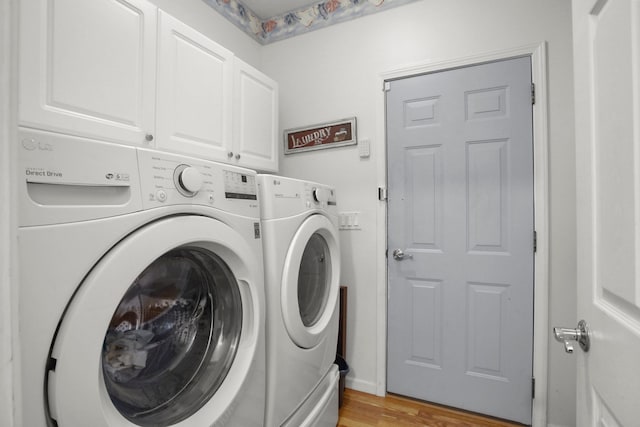 washroom with washing machine and clothes dryer, cabinet space, and light wood-style flooring