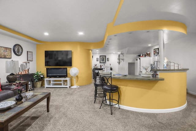 interior space with baseboards, a kitchen bar, carpet floors, recessed lighting, and fridge