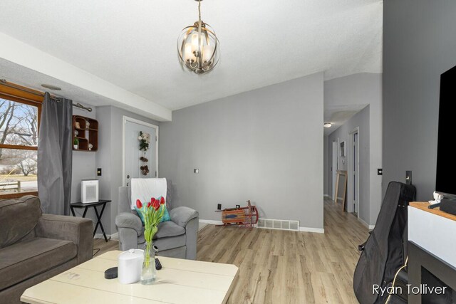 living room featuring lofted ceiling, light wood finished floors, visible vents, and baseboards