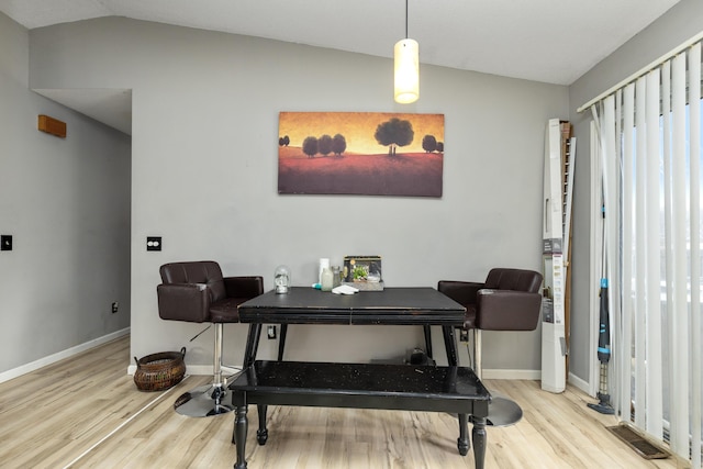 dining room featuring vaulted ceiling, wood finished floors, visible vents, and baseboards