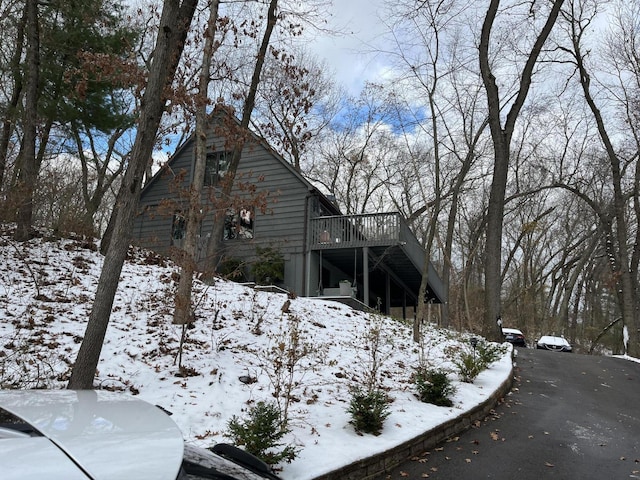 view of snow covered exterior featuring stairs and a wooden deck