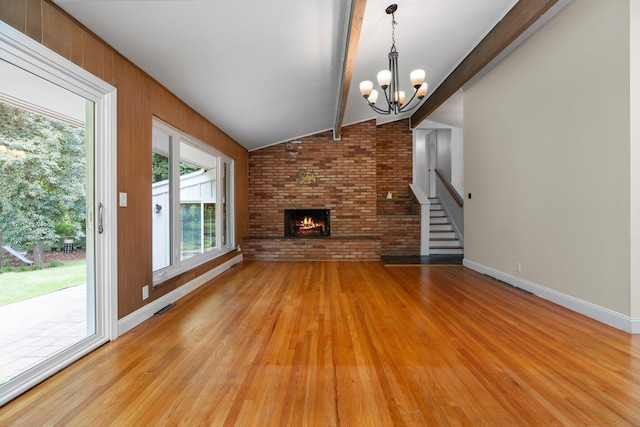 unfurnished living room featuring vaulted ceiling with beams, baseboards, stairway, light wood-type flooring, and a brick fireplace