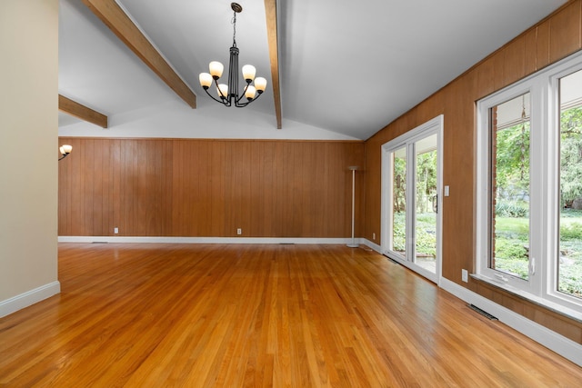 unfurnished room featuring lofted ceiling with beams, light wood-style flooring, a notable chandelier, wood walls, and visible vents