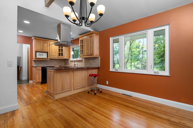 kitchen featuring dark countertops, backsplash, white microwave, glass insert cabinets, and island range hood