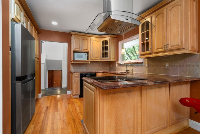 kitchen with island range hood, glass insert cabinets, dark stone countertops, a peninsula, and black appliances