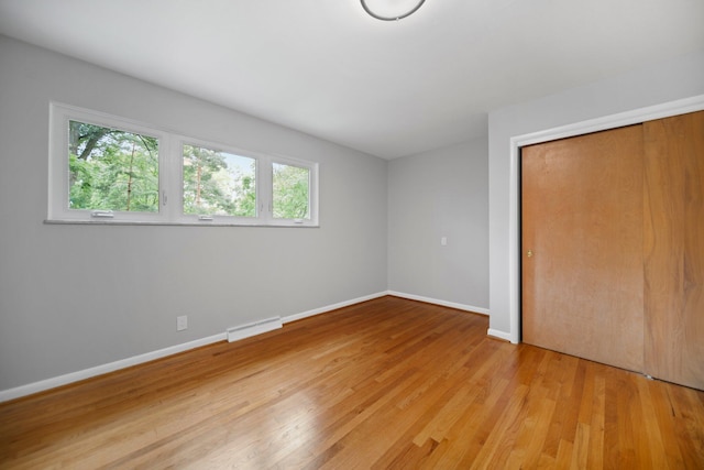 unfurnished bedroom featuring light wood-type flooring, baseboards, visible vents, and a closet