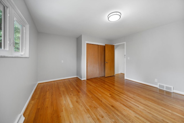 unfurnished bedroom with light wood finished floors, a closet, visible vents, and baseboards