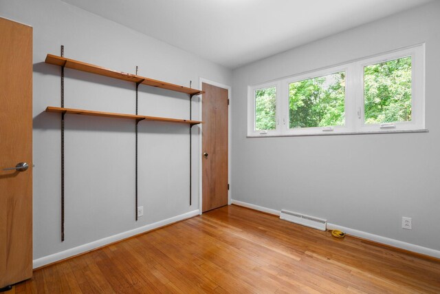 unfurnished bedroom featuring baseboards, multiple windows, visible vents, and hardwood / wood-style floors