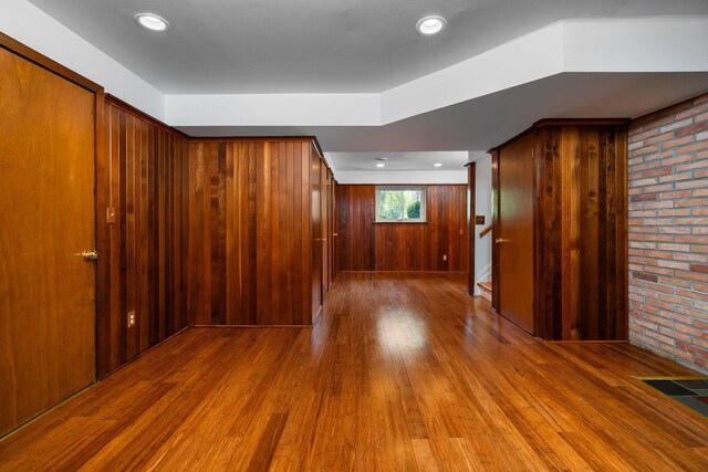 empty room featuring stairway, visible vents, wooden walls, and wood finished floors