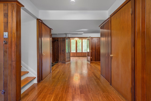 hallway with light wood-style flooring, stairs, and baseboards