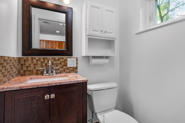 half bath with toilet, backsplash, and vanity