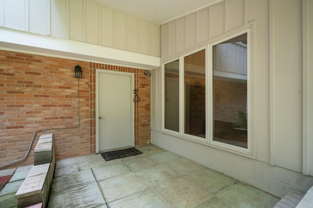 entrance to property featuring board and batten siding and brick siding