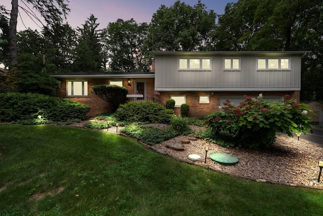 split level home with a lawn and brick siding