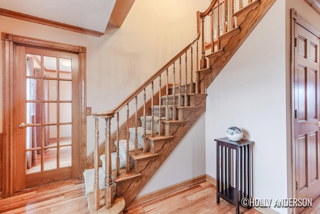 stairway with crown molding, wood finished floors, and baseboards