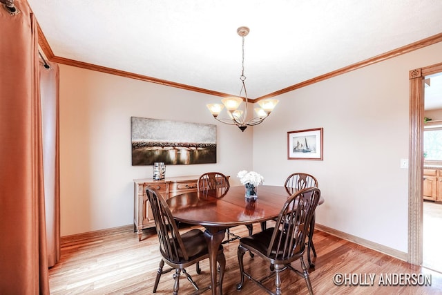 dining room with light wood-style floors, crown molding, and an inviting chandelier