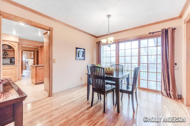 dining space with a textured ceiling, light wood-style flooring, an inviting chandelier, washer / dryer, and crown molding