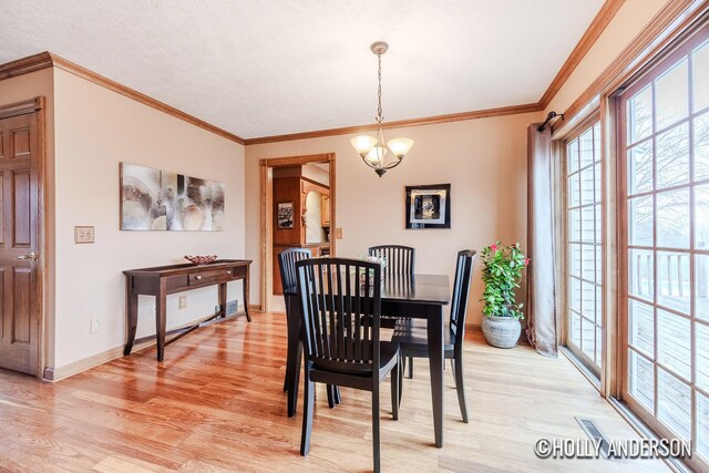 dining area featuring ornamental molding, light wood finished floors, baseboards, and a notable chandelier