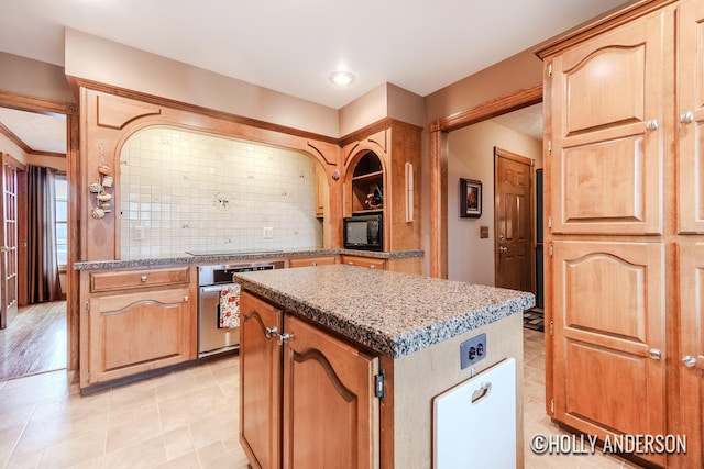 kitchen featuring black appliances, a kitchen island, light stone countertops, and decorative backsplash