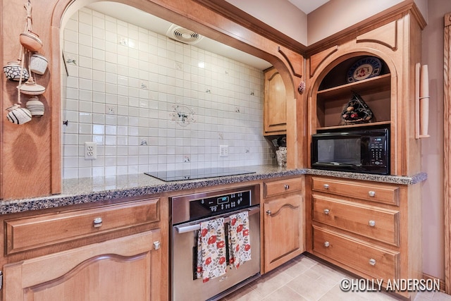 kitchen with black appliances, tasteful backsplash, light tile patterned floors, and brown cabinets