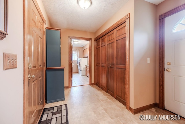 foyer entrance with baseboards, washer and dryer, and a textured ceiling