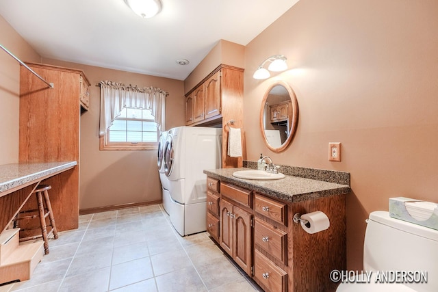 washroom with light tile patterned floors, cabinet space, a sink, separate washer and dryer, and baseboards