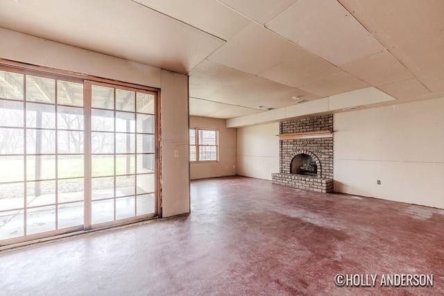 unfurnished living room with a brick fireplace and concrete floors