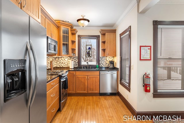 kitchen with crown molding, open shelves, appliances with stainless steel finishes, brown cabinetry, and a sink