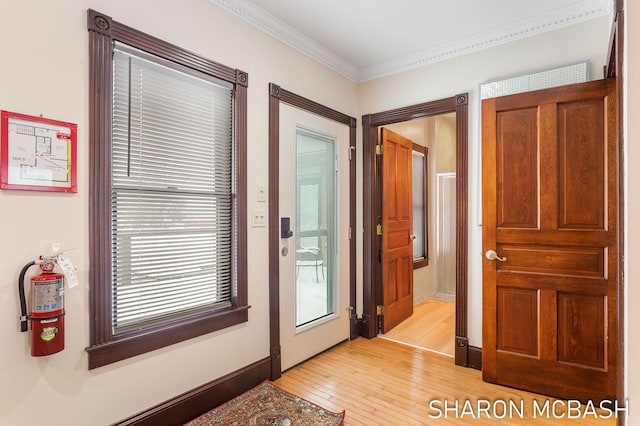 doorway featuring ornamental molding, light wood-style flooring, and baseboards