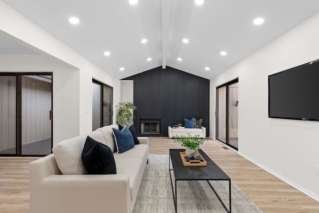 living area featuring a large fireplace, baseboards, light wood-type flooring, lofted ceiling with beams, and recessed lighting